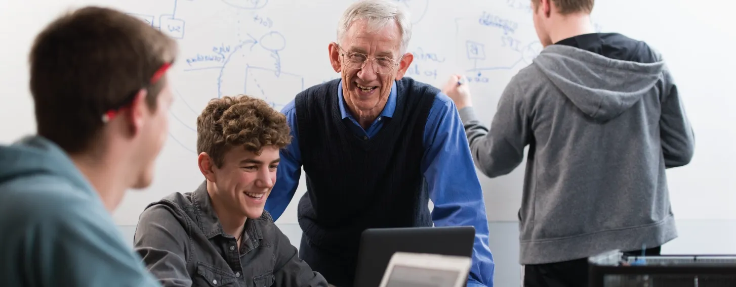 Computer science professor in classroom helping students.